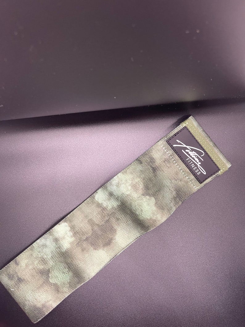 May include: A green and brown camouflage exercise band with the text "Julianna Fitness" printed on the band.