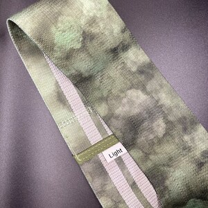 May include: A green and white fabric resistance band with the word "Light" printed on it.