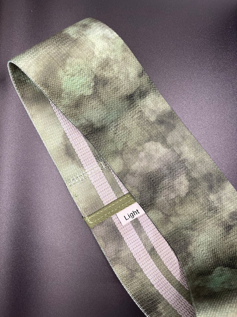 May include: A green and white fabric resistance band with the word "Light" printed on it.