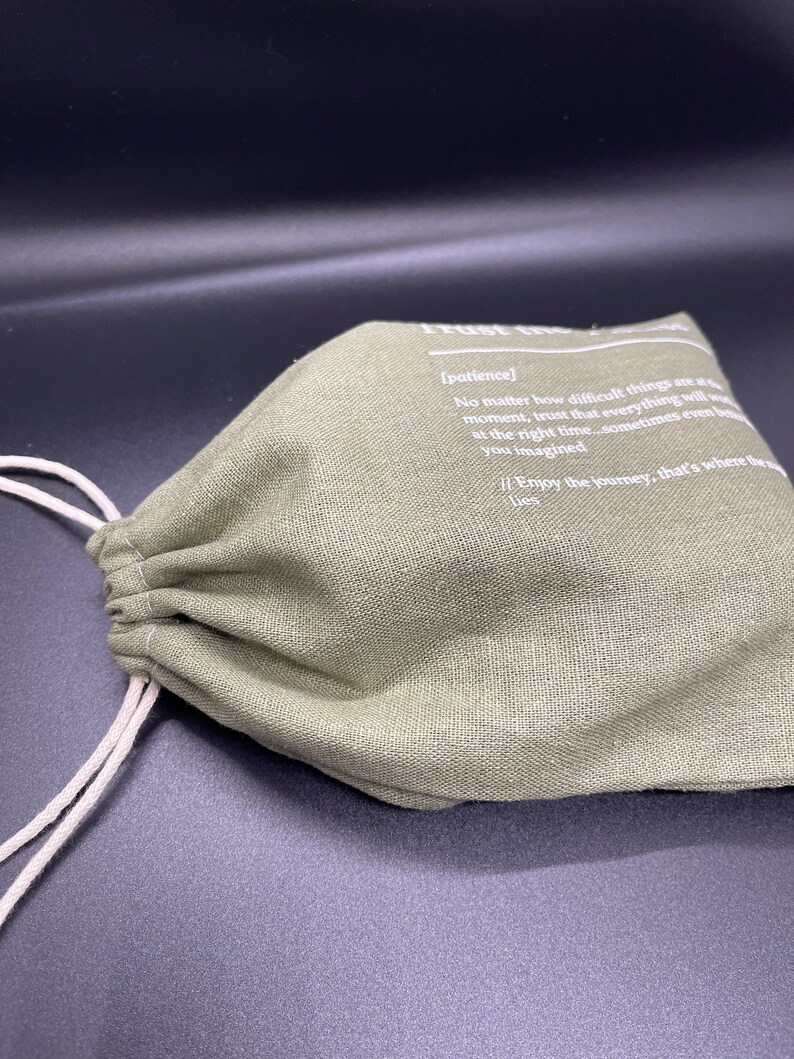 May include: A green drawstring bag with a white text quote that reads: "[patience] No matter how difficult things are at the moment, trust that everything will work out at the right time...sometimes even better than you imagined. Enjoy the journey, that's where the magic lies."