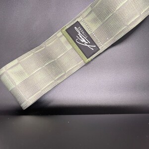 May include: A green fabric resistance band with a black label that says "Fitness".