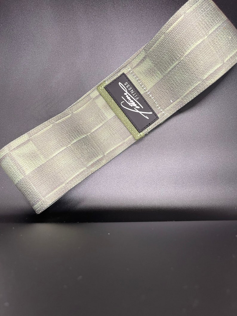 May include: A green fabric resistance band with a black label that says "Fitness".