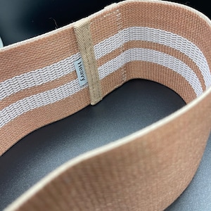 May include: A brown fabric resistance band with two white stripes and the word "Heavy" printed on it.