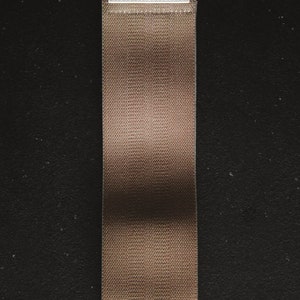 May include: A brown fabric resistance band with a white label that says "Fitness" in black text.