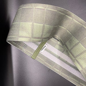 May include: A green and white patterned fabric resistance band with the word "Heavy" printed on it.