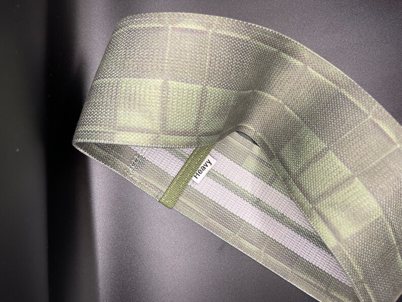 May include: A green and white patterned fabric resistance band with the word "Heavy" printed on it.