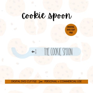 May include: A digital SVG cut file for a cookie spoon. The design features a blue cookie spoon with the text "The Cookie Spoon" and a white arrow pointing to the left. The text "Dip Here" is written above the arrow. The design is surrounded by a pattern of brown and white cookies.