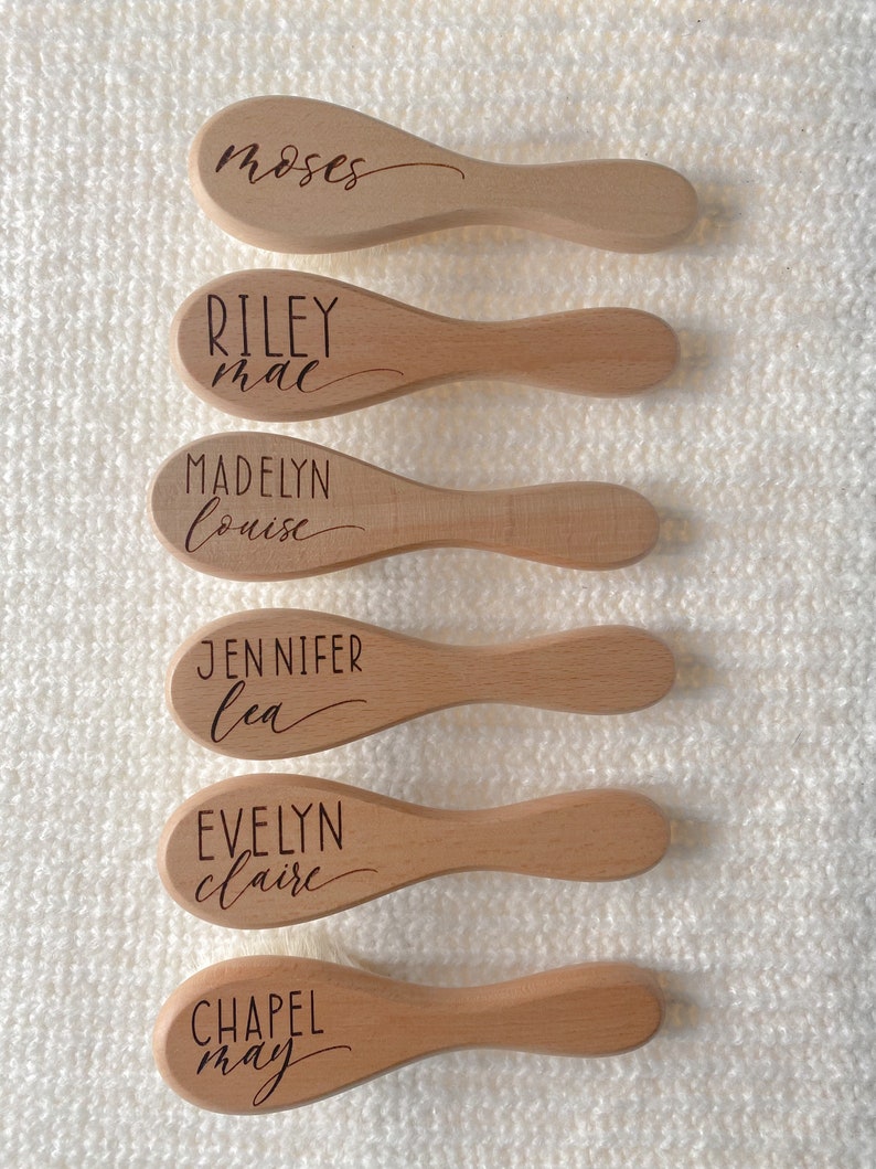 May include: Six wooden hairbrushes with personalized names engraved on them. The names are Moses, Riley Mae, Madelyn Louise, Jennifer Lea, Evelyn Claire, and Chapel May.