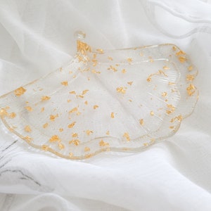 May include: A clear glass tray shaped like a ginkgo leaf with gold flecks throughout.
