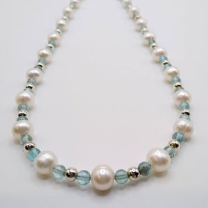 May include: A white pearl and light blue gemstone necklace. The necklace is made with alternating white pearls and light blue gemstones. The necklace has a silver clasp.