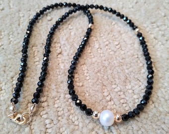 Black spinel faceted round beaded necklace centered with a white freshwater pearl and round gold beads.  Minimalist design.