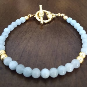 Aquamarine beaded bracelet with round gold corrugated beads and a gold toggle clasp.