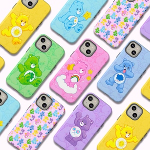 Może przedstawiać: Kolekcja kolorowych etui na telefony z różnymi wzorami Care Bears. Etui prezentują różne misie w odcieniach żółci, błękitu, zieleni, różu i fioletu. Każde etui ma unikalny design, w tym tęcze, serca i chmury.