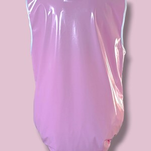 May include: A light pink, sleeveless bodysuit with a white trim around the neckline and armholes. The shiny, waterproof material has a smooth, reflective surface. The bodysuit is designed to cover the torso and lower body.