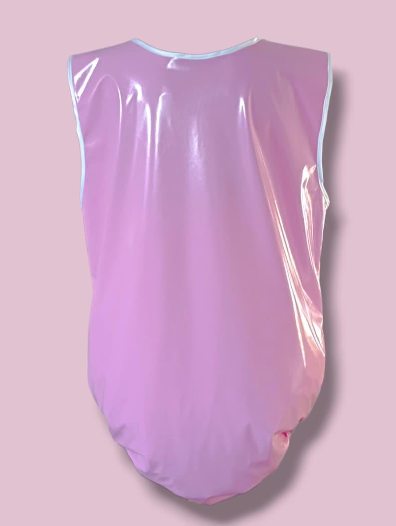 May include: A light pink, sleeveless bodysuit with a white trim around the neckline and armholes. The shiny, waterproof material has a smooth, reflective surface. The bodysuit is designed to cover the torso and lower body.
