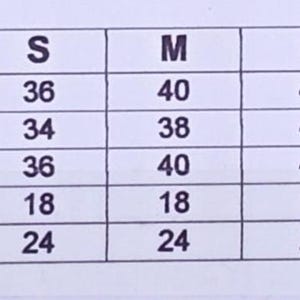May include: Dress size chart with measurements in inches. Includes chest, waist, hips, shoulders, and sleeve length for sizes XS to 3XL. Measurements range from 86 cm to 127 cm.