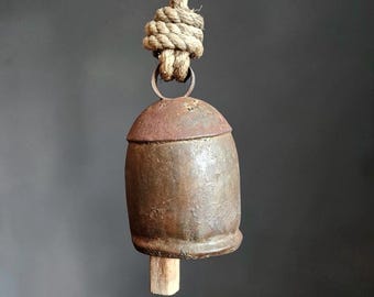 Sino de vaca rústico vintage em metal com badalo de madeira e suporte para corda, decoração primitiva de fazenda.