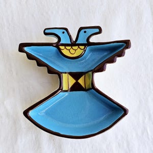 May include: A blue ceramic dish shaped like a stylized bird with brown and yellow accents. The dish has two heads and a wide, flat base.