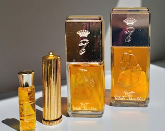 May include: An assortment of vintage perfume bottles in various sizes. The bottles are filled with a golden liquid and feature gold-colored caps and accents. The bottles are labeled "White Shoulders" and have a woman's silhouette on the front.