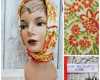 May include: A vintage headscarf with a floral pattern in shades of red, orange, yellow, and green. The scarf is made of acetate twill and has a label that reads "Acetate Twill Acetate CA 00098 Made in Japan."