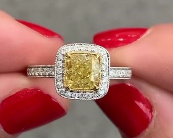 May include: A gold ring with a large, cushion-cut yellow diamond surrounded by a halo of smaller diamonds.