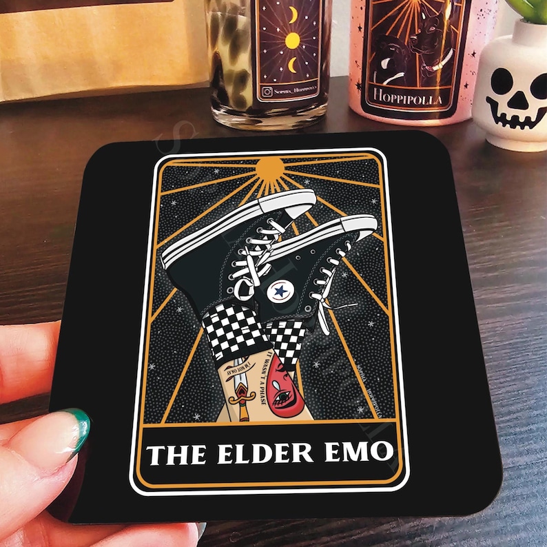 May include: A black and gold tarot card with a black background and gold accents. The card features a pair of black and white checkered Converse sneakers with a red eye and a dagger on the ankle. The card is titled "The Elder Emo".