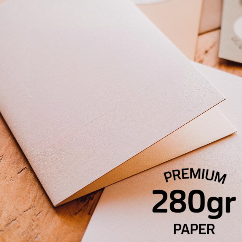 May include: A folded light beige card made of thick, textured material. The bottom right corner features black text that reads PREMIUM 280gr PAPER. The card has a matte finish and a clean, simple design, showcasing the quality of the heavy paper stock.