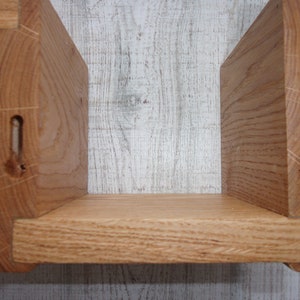 K&ouml;nnte beinhalten: Ein Holzregal mit zwei Regalbrettern. Die Regalbretter sind aus massivem Holz und haben eine nat&uuml;rliche Oberfl&auml;che. Das Regal ist f&uuml;r die Wandmontage konzipiert.