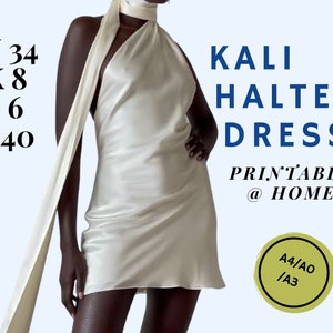 May include: A white halter dress with a long, flowing scarf. The dress is a simple, elegant design with a fitted bodice and a flowing skirt. The text "KALI HALTER DRESS PRINTABLE @ HOME A4/AO /A3" is printed on the image.