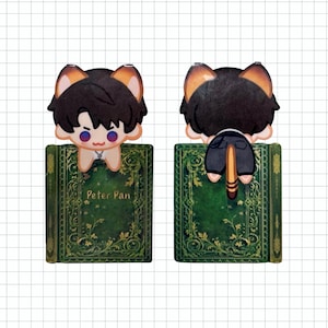 May include: A pair of decorative bookmarks featuring a cartoon character with black hair and cat ears, perched on a green book. The book is titled "Peter Pan" in white text. One bookmark shows the front, the other the back.