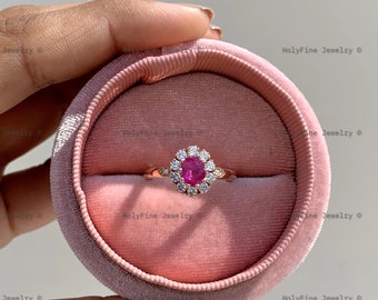 May include: A rose gold ring with a pink gemstone surrounded by smaller white gemstones. The ring is in a pink velvet ring box.