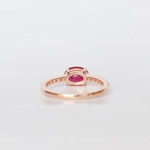 K&ouml;nnte beinhalten: Ein Ring aus Ros&eacute;gold mit einem roten ovalen Edelstein und einer Reihe kleiner Diamanten.