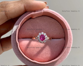 Könnte beinhalten: Ein Ring aus Roségold mit einem rosafarbenen Edelstein, der von kleineren weißen Edelsteinen umgeben ist. Der Ring befindet sich in einer rosafarbenen Samt-Ringbox.