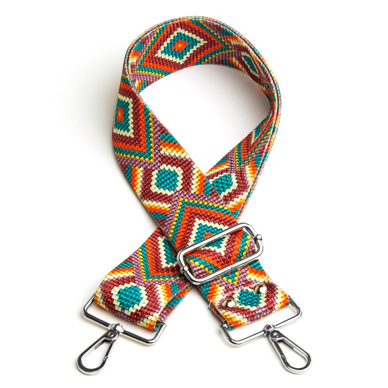 May include: A colorful woven strap with a geometric pattern in shades of orange, red, green, and white. The strap has silver metal clasps on each end.