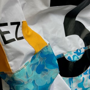 May include: A white jacket with a black number "5" on the back and the word "EZ" on the left sleeve. The jacket has a yellow stripe on the sleeve and a blue camouflage pattern on the bottom.