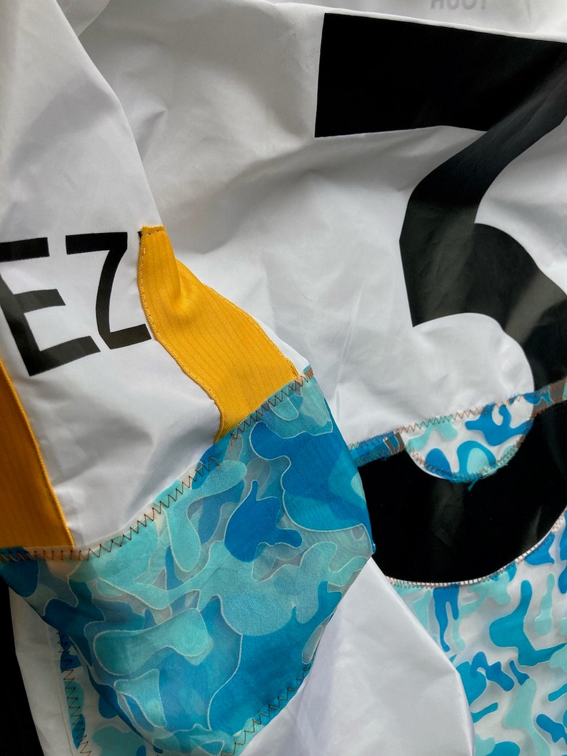 May include: A white jacket with a black number "5" on the back and the word "EZ" on the left sleeve. The jacket has a yellow stripe on the sleeve and a blue camouflage pattern on the bottom.