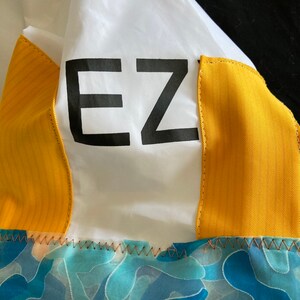 May include: A white jacket with yellow panels and a blue and green camouflage pattern on the bottom. The jacket has the word "EZ" printed on the front.