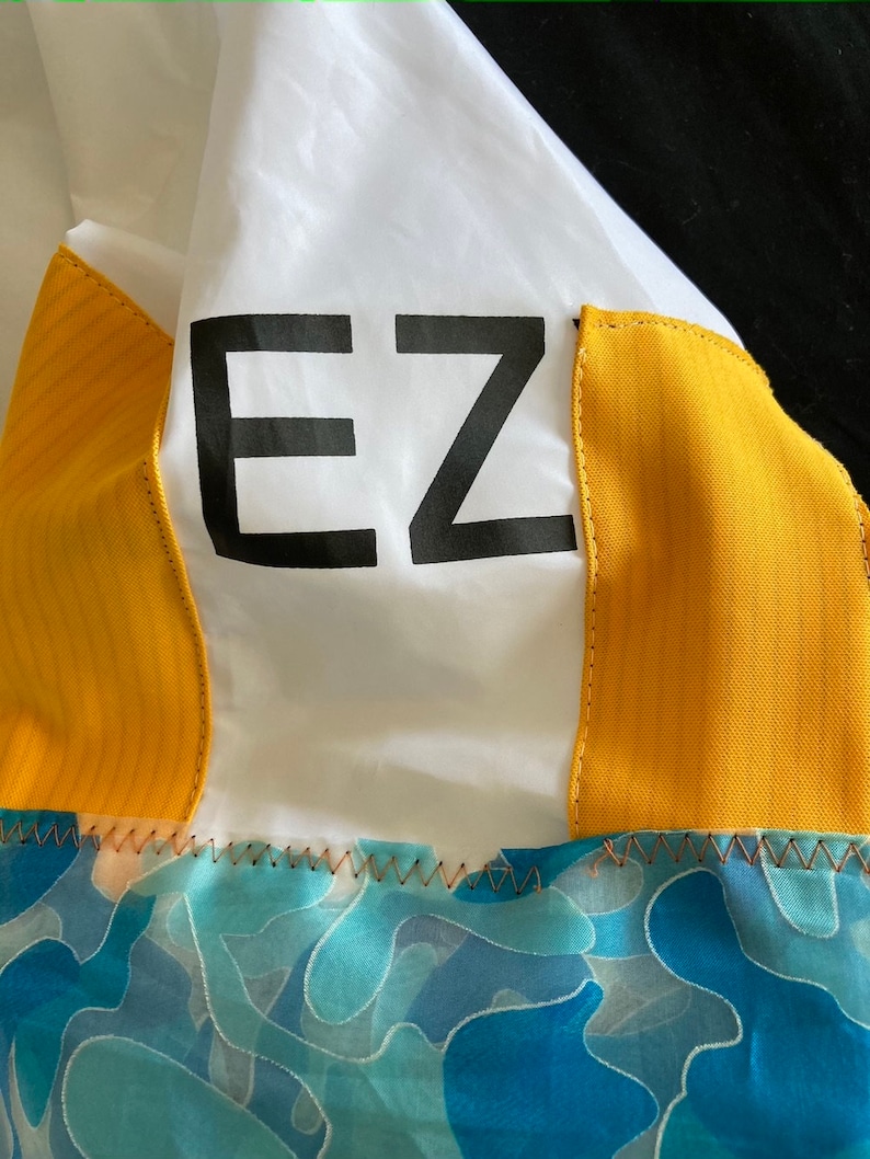 May include: A white jacket with yellow panels and a blue and green camouflage pattern on the bottom. The jacket has the word "EZ" printed on the front.