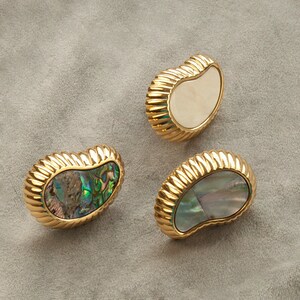 May include: Three gold-toned, decorative cabinet knobs with a scalloped edge. The knobs are made of metal and have a mother-of-pearl inlay. The inlays are in shades of white, green, and blue.