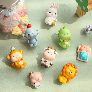 May include: A set of ten small, colourful figurines of various animals, including a bunny, a cow, a lion, a monkey, a pig, a dinosaur, and an elephant. The figurines are made of plastic and have a cartoonish style.