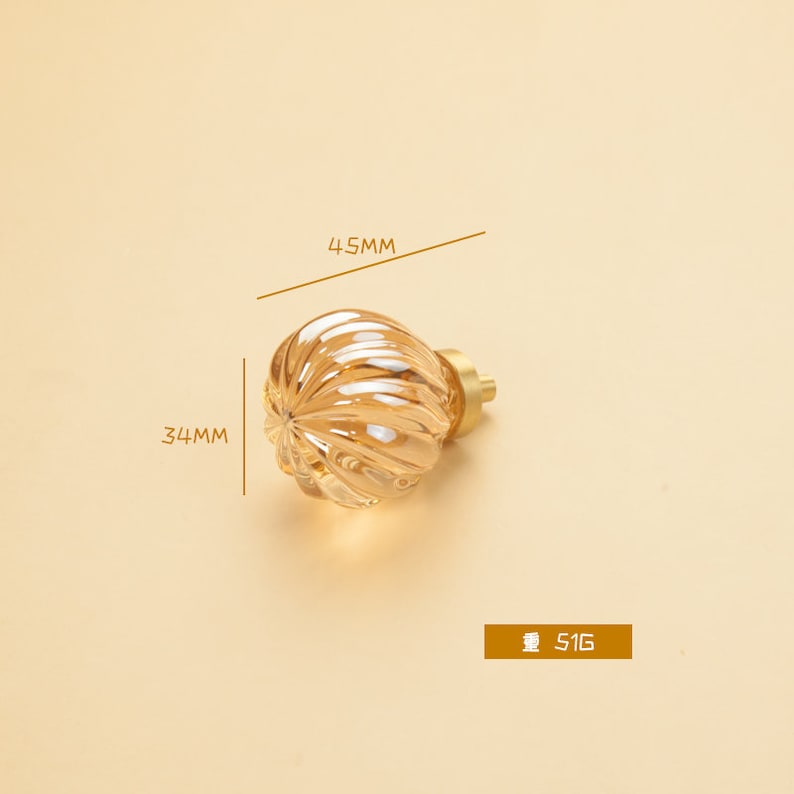 May include: A gold-toned glass cabinet knob with a ribbed design. The knob measures 4.5 cm in diameter and 3.4 cm in height.