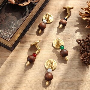 Peut inclure: Ensemble de boutons de meubles d&eacute;coratifs. Chaque bouton comprend une sph&egrave;re en bois fonc&eacute;, des &eacute;l&eacute;ments en laiton et des perles color&eacute;es. Id&eacute;al pour les projets de meubles et de d&eacute;coration int&eacute;rieure.