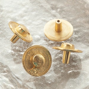 May include: Four gold-toned cabinet knobs shaped like miniature straw hats. Each knob has a raised, textured design and a small, round hole in the centre.