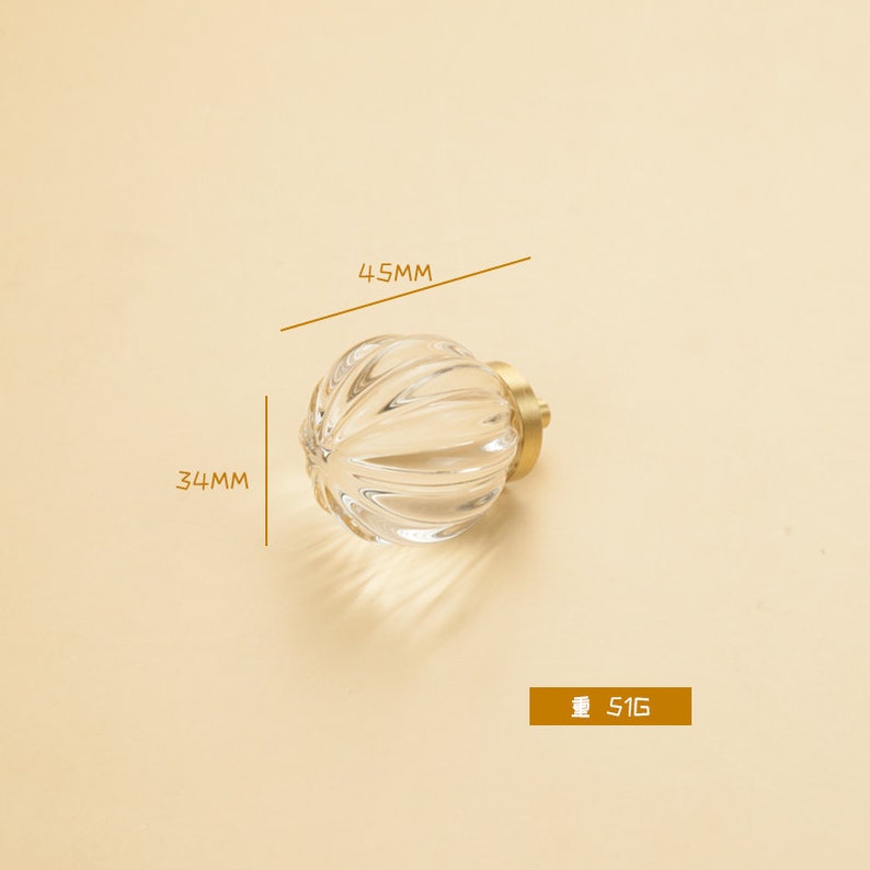 May include: A clear glass cabinet knob with a ribbed design and a gold metal base. The knob measures 4.5 cm in diameter and 3.4 cm in height.