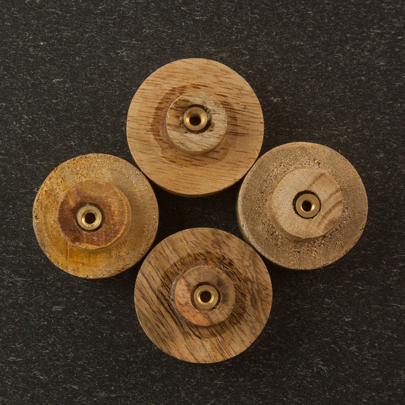 K&ouml;nnte beinhalten: Vier Holzspulen mit Messing-Eins&auml;tzen in der Mitte. Die Spulen sind in einer Diamantform auf einer dunkelgrauen Oberfl&auml;che angeordnet.