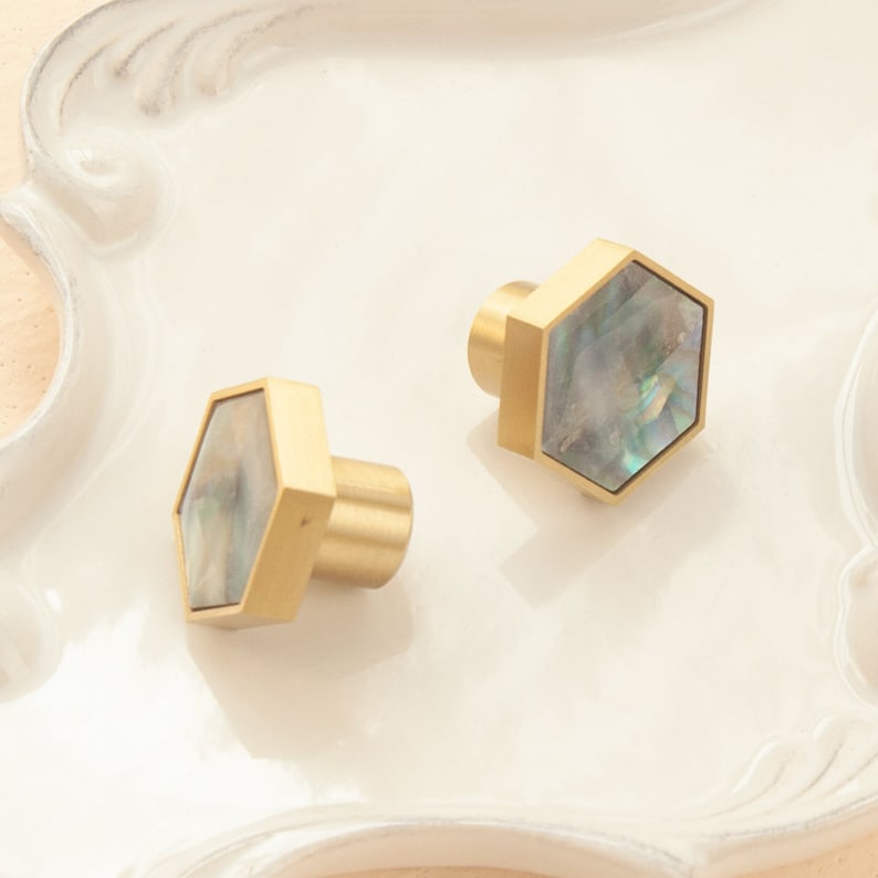May include: Two gold hexagonal cabinet knobs with iridescent mother of pearl inlays.