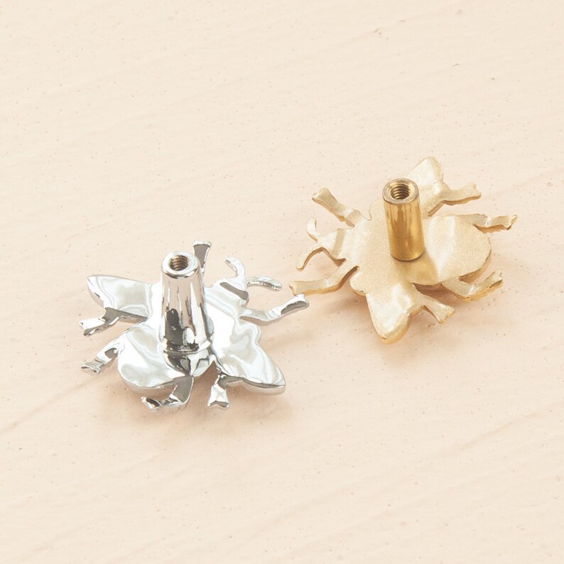 Peut inclure: Deux boutons de porte en forme d'abeille, l'un en argent et l'autre en or. Les boutons ont un design d'abeille d&eacute;taill&eacute; avec des ailes et des pattes.