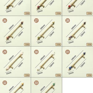 Op de afbeelding: Een verzameling messing kastgrepen met decoratieve edelsteenaccenten. Elke greep is 240 mm lang, 128 mm hoog en 33 mm breed. De grepen hebben edelstenen in verschillende kleuren, waaronder rood, groen en wit.