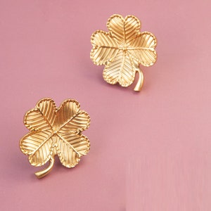 Peut inclure: Une paire de boucles d'oreilles en forme de tr&egrave;fle &agrave; quatre feuilles de couleur dor&eacute;e. Les boucles d'oreilles sont en m&eacute;tal et ont une surface textur&eacute;e.