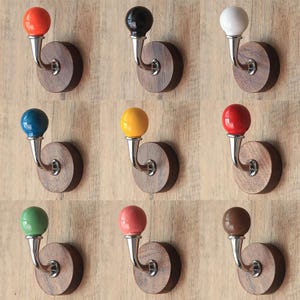 Può includere: Nove ganci da parete decorativi con pomelli in ceramica di diversi colori. Ogni gancio è montato su una base rotonda in legno.